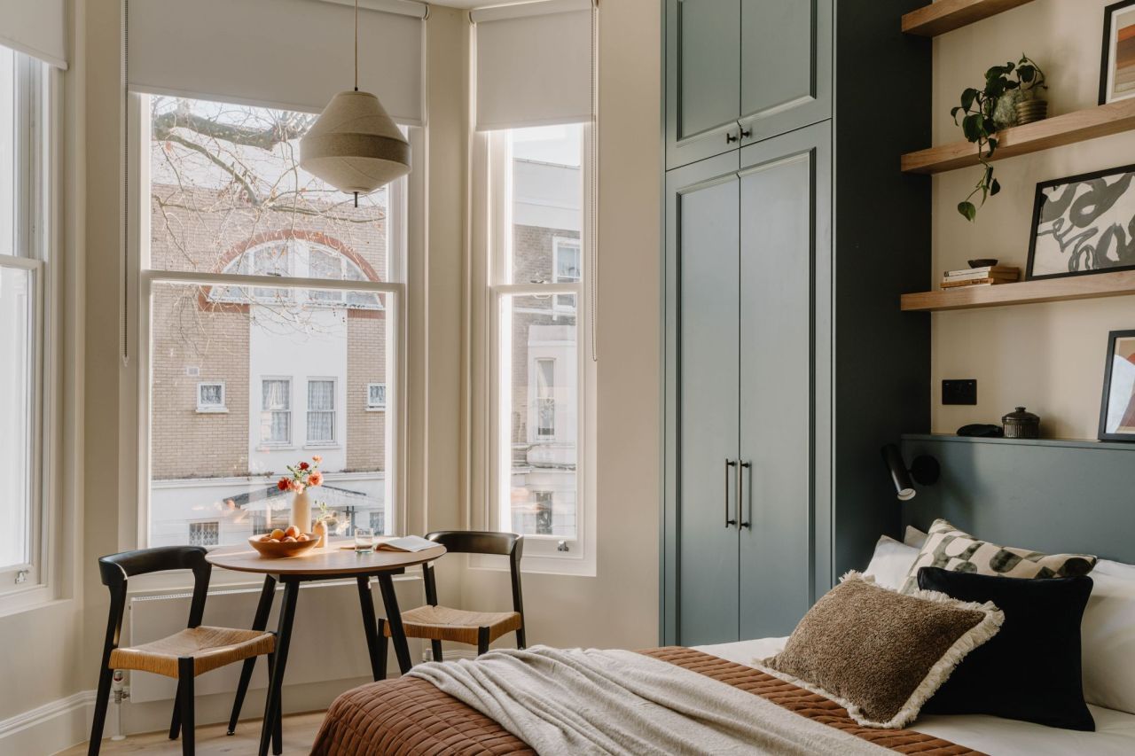 Bedroom with bespoke green joinery and bay window dining nook
