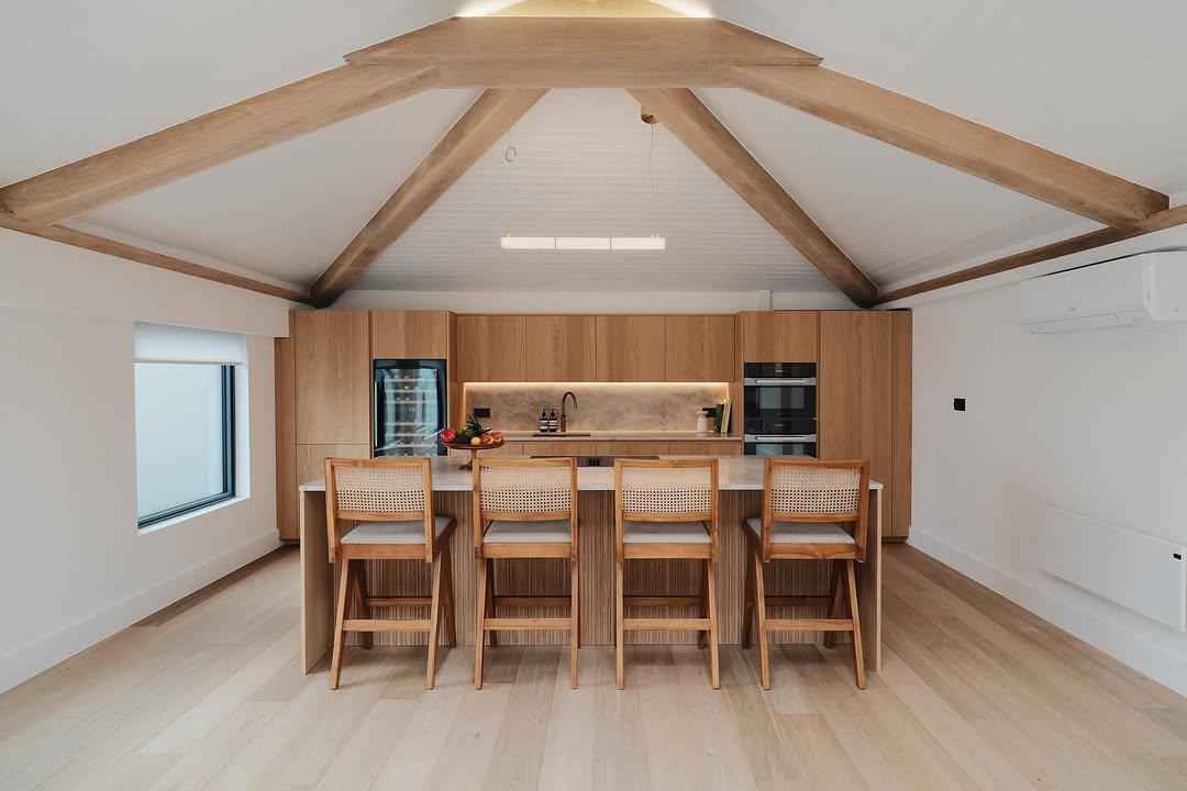 Modern oak kitchen with island seating under a vaulted beam ceiling