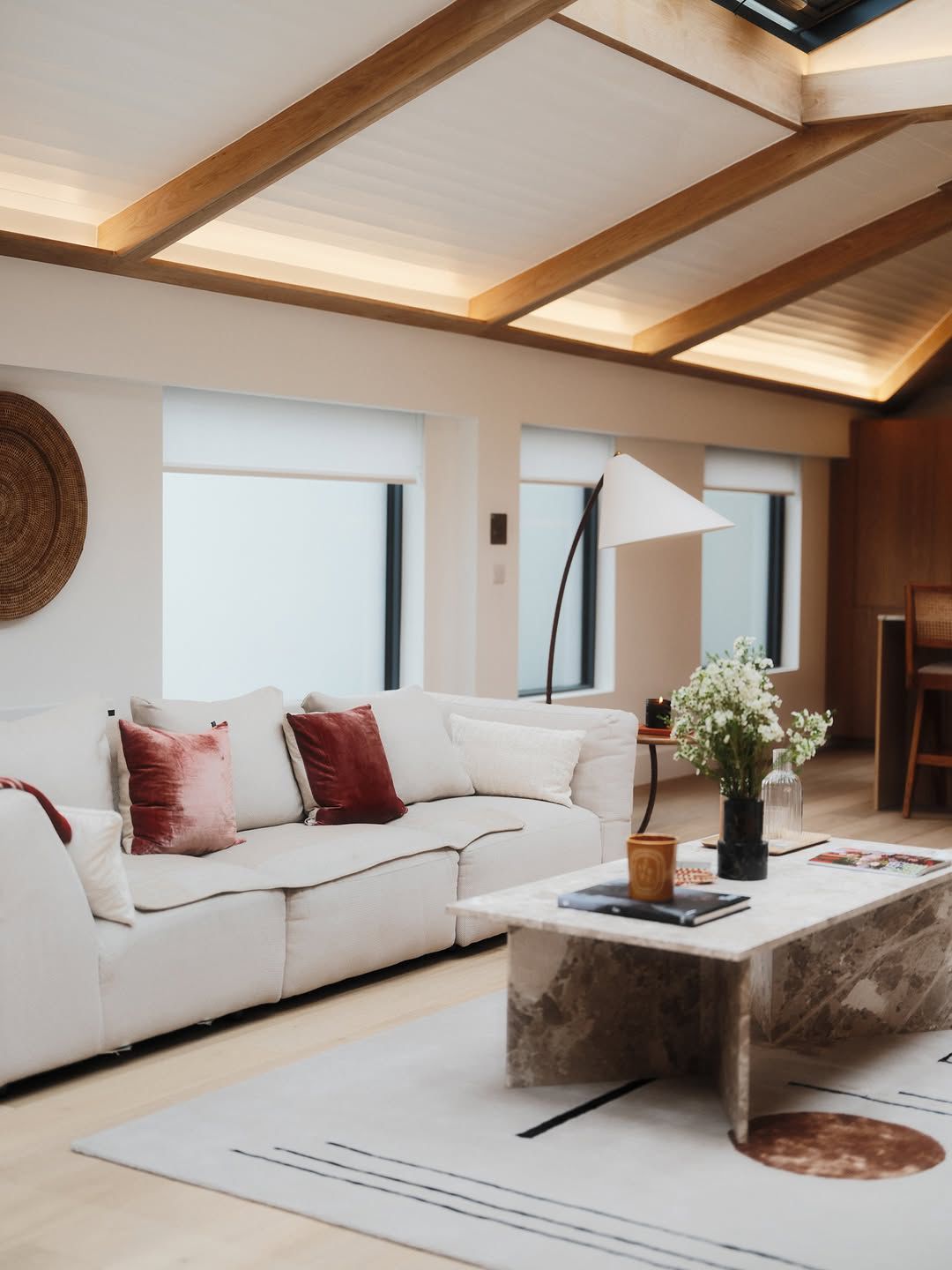 Living room with neutral sofa, marble coffee table and oak beam ceiling