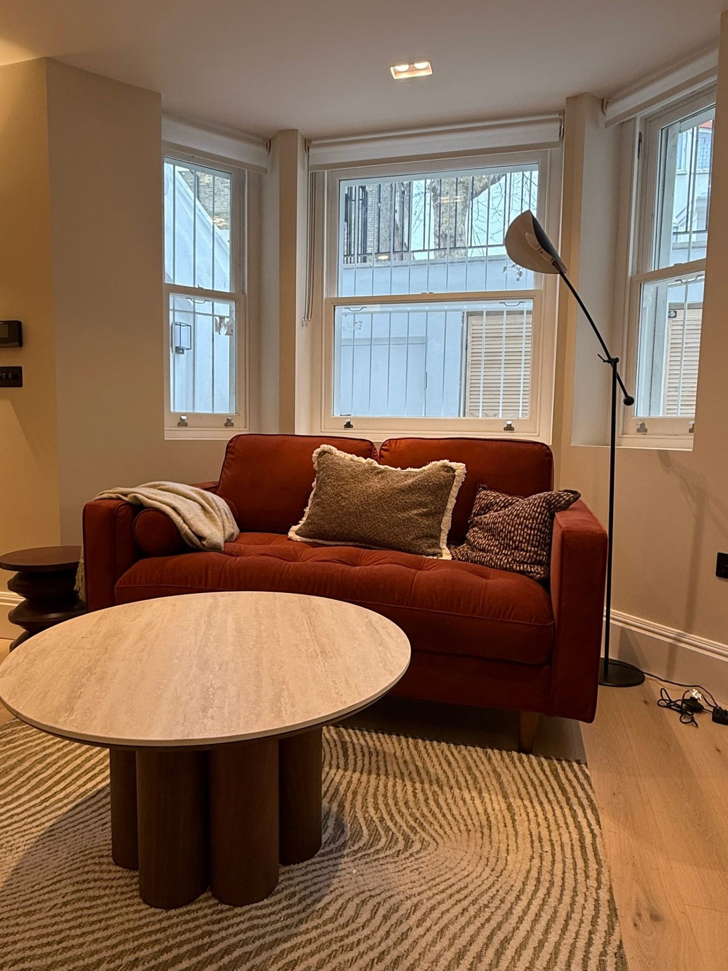 Lounge with bay window, terracotta sofa and travertine coffee table